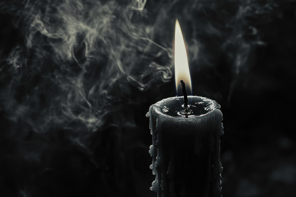 Black Candle lit with smoke on a black background